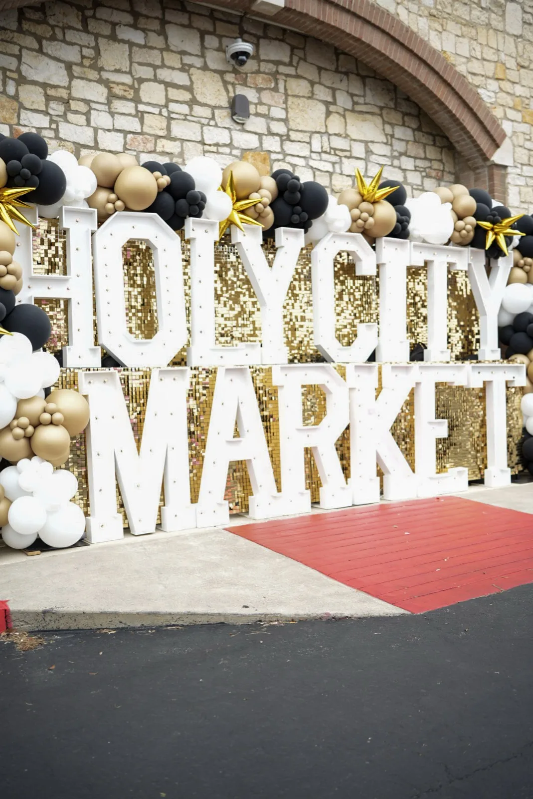 The Holy City Market entrance marquee with the CBC West stone arch framing the backdrop.