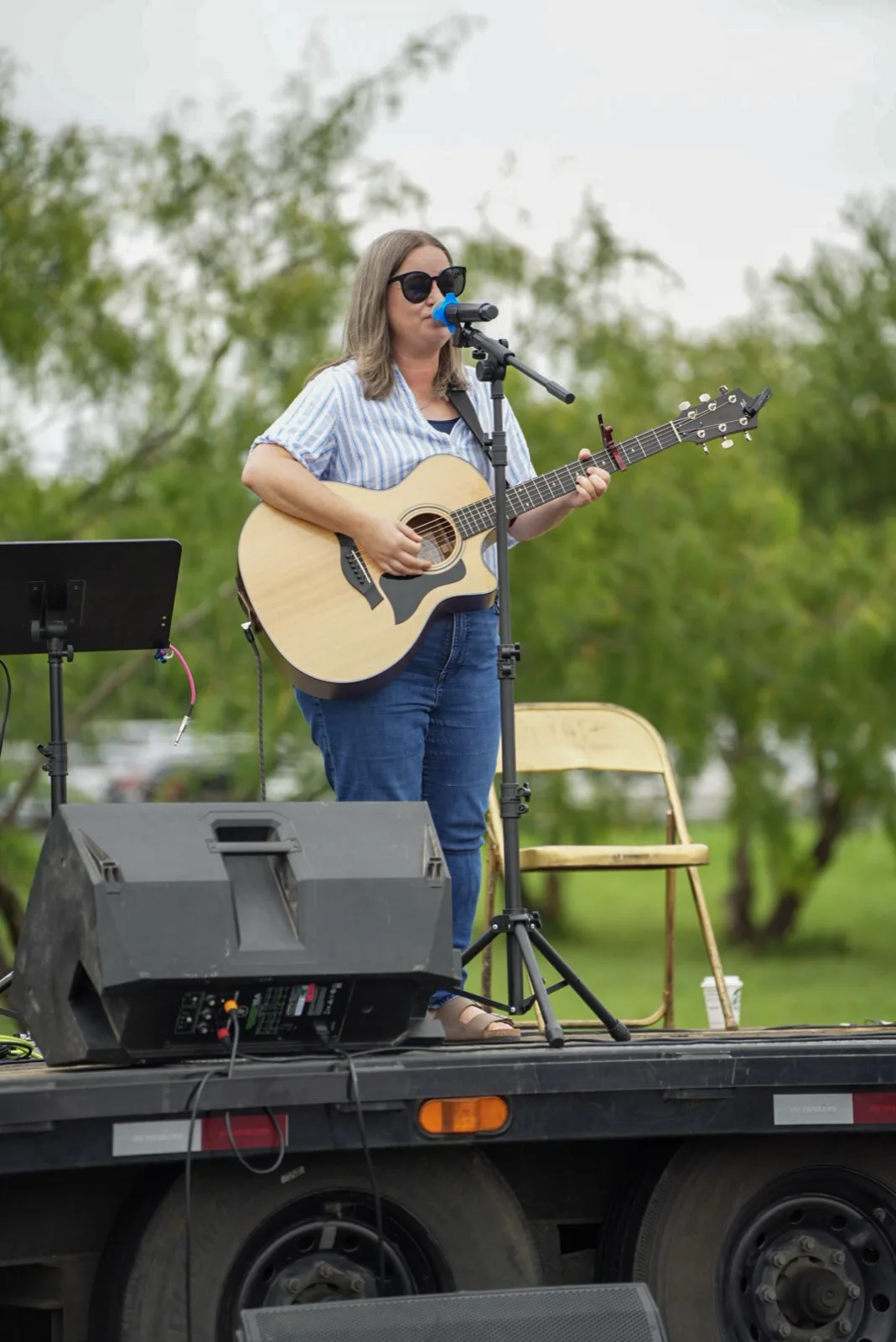 A woman plays acoustic guitar and sings on the outdoor stage at Holy City Market.