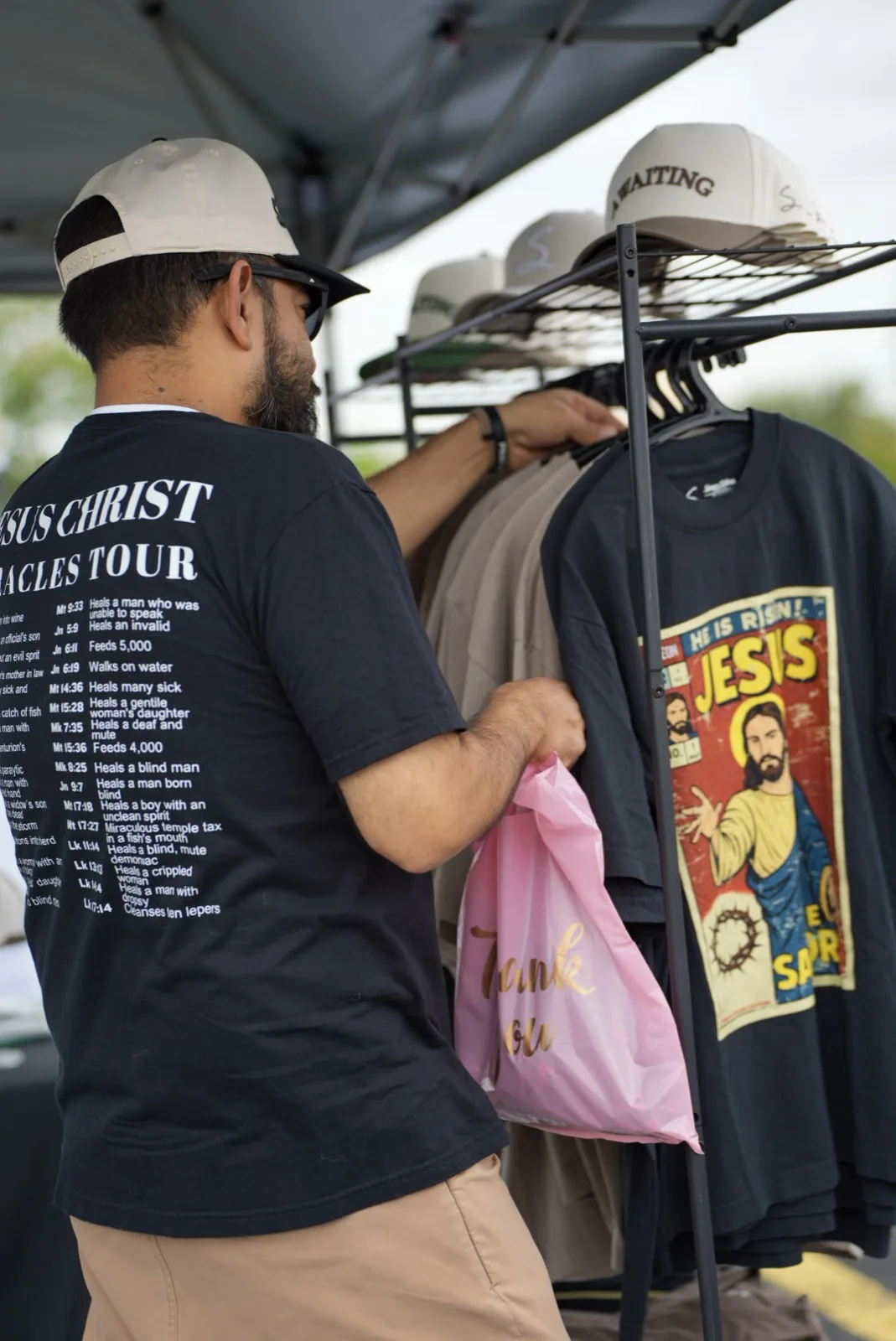 A man browses Jesus-themed shirts and hats at a vendor booth at Holy City Market.