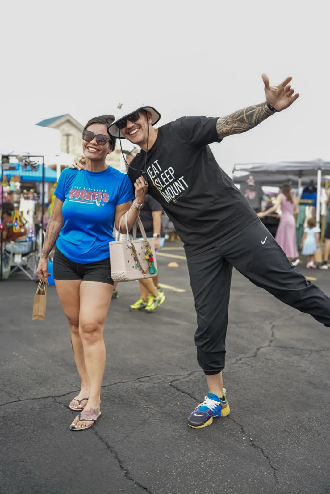 A laughing couple enjoying Holy City Market, the woman in a Rockets jersey.